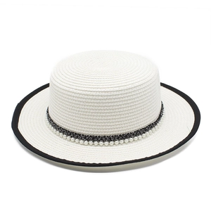 Detail of white straw boater hat featuring pearl strand accent and black contrast trim