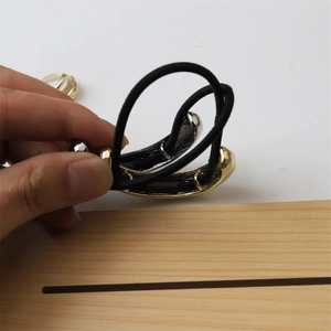 Close-up of black elastic hair tie featuring a textured gold metal buckle clasp