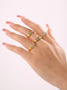 Detail of gold stacked rings with colorful zircon stones and white faux pearls on fingers