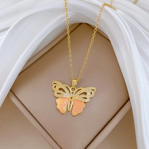 Detailed close-up of a golden butterfly pendant with pink crystals in a beige jewelry box