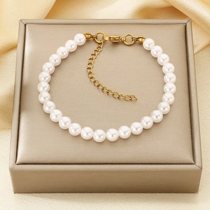 Detail of elegant pearl bracelet with golden lobster clasp and heart charm on a jewelry box