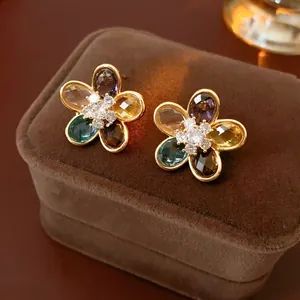 Elegant gold flower earrings with multicolor zircons and crystals on a brown velvet box