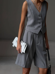 Detail of dark grey vest and high-waist shorts suit set with minimalist tailoring