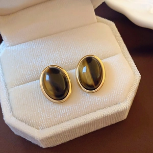 Macro shot of retro oval earrings with brown resin stone in gold bezel on velvet box