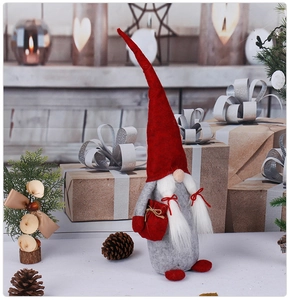 Close-up of a festive Nordic Christmas gnome with red hat and gray felt body in cozy setting