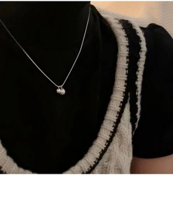 Detail of s925 sterling silver necklace with dual pearls worn by a model on a dark vest
