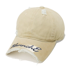 Macro detail of beige canvas baseball cap with vintage distressed edges and blue embroidery