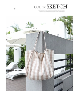 Close-up of a striped beige and white canvas tote bag hanging on a sunny pool terrace