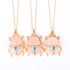 Pink crystal beetle pendant necklace with blue eye detail on a gold chain for women