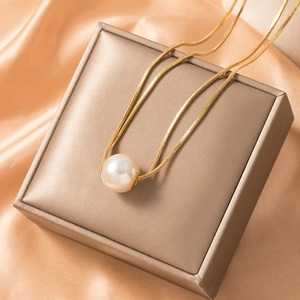 Elegant gold snake chain necklace with a 10mm round white pearl on a jewelry box
