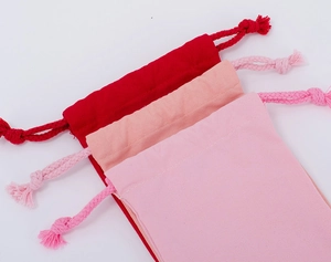 Detailed view of red, peach and pink cotton drawstring bags showing fabric texture