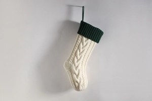 Close-up of cream cable knit Christmas stocking with dark green ribbed cuff detail