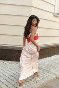 Detail of red lace trim on a beige satin maxi dress with slim red straps for women