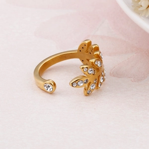 Bague ouverte feuille dorée avec zircons brillants sur fond rose doux élégant