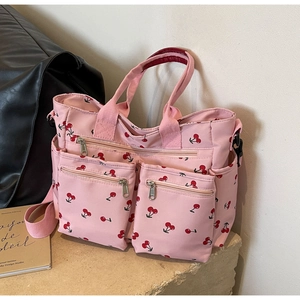 Detail view of pink tote bag with cherry print on a stone surface showing zipper pockets