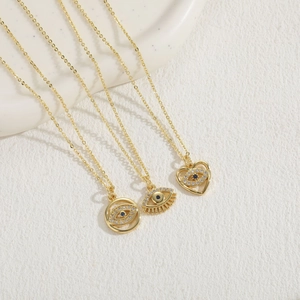 Three gold evil eye necklaces with zircon in round, eye, and heart shapes on textured tray