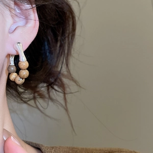 Détail de boucles d'oreilles créoles vintage avec perles en pierre brune et crochet argent