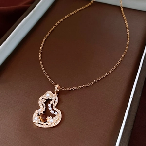 Detailed close-up of a golden gourd pendant necklace with pearls and tiger eye stone