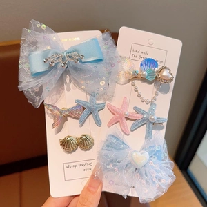 Détail de barrettes thème marin avec nœuds en dentelle bleue et queues de sirène brillantes