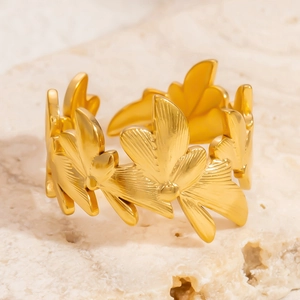 Close-up of a gold-plated adjustable leaf-shaped ring on a textured stone surface