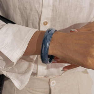 Detail of dark blue resin round geometric bangle worn on wrist for a minimalist retro look