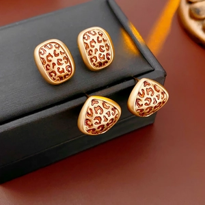 Vue détaillée de boucles d'oreilles géométriques léopard avec bords dorés sur coffret