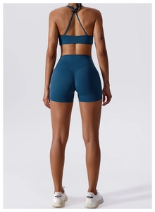 Detail of cross-back sports bra and high-waisted lifting shorts in deep teal fabric