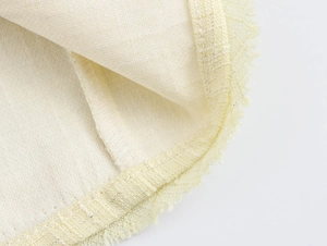 Détail macro du tissu en tweed jaune clair avec bords effilochés et coutures précises