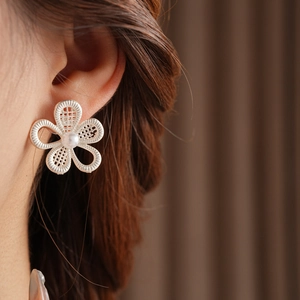 Vue détaillée de boucles d'oreilles fleur évidée en argent avec perle sur un mannequin