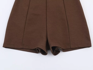 Detailed close-up of dark brown twill fabric texture and clean hem stitching on shorts