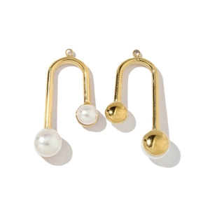 Detail of elegant gold arched earrings featuring a white pearl and a metallic gold bead