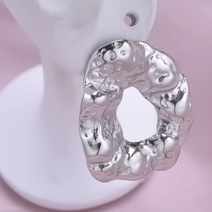 Close-up of irregular silver 304 stainless steel earrings with hammer texture on model