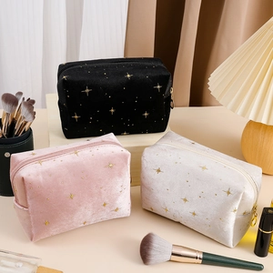Detailed shot of velvet cosmetic bags in black, pink and beige with gold star patterns