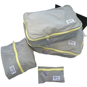 Gray grid pattern travel organizer set with bright yellow zippers and purple pull tabs