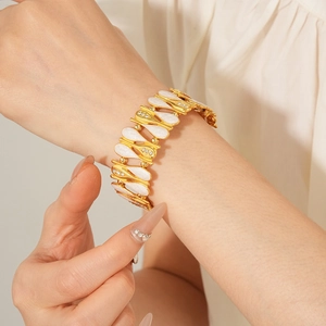 Close-up of vintage golden leaf bracelet with white enamel and sparkling zircon details