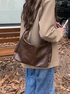Detail of dark brown vintage hobo bag in soft textured leather with golden hardware