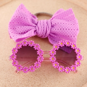 Flat lay of pink daisy flower sunglasses with matching mesh bow headband for kids