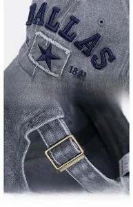 Close-up of distressed denim baseball cap with Dallas embroidery and adjustable metal buckle