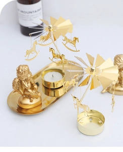 Macro shot of gold rotating candle holder with carousel pendants and angel statue on a tray