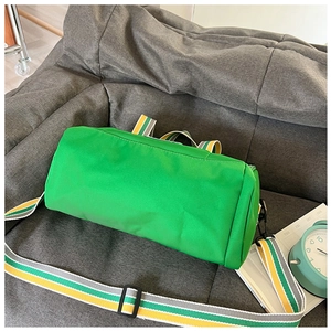 Detail of green cylinder sports bag with striped shoulder strap on a gray sofa