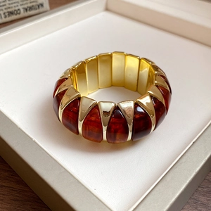 Detail of amber acrylic and gold metal wedge-shaped segments on an elastic bracelet