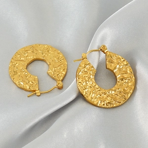 Textured gold-plated stainless steel hoop earrings on elegant silver satin fabric