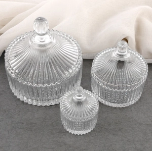 Three-piece set of vertical ribbed glass jars with ball handles in various sizes