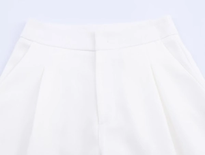 Macro detail of white linen trousers waistline showing fabric texture and side pockets