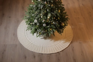 Detailed view of cream-colored knitted Christmas tree skirt with textured weaving pattern