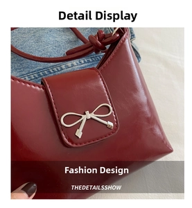 Close-up of a burgundy bucket bag with silver bow buckle against denim backdrop
