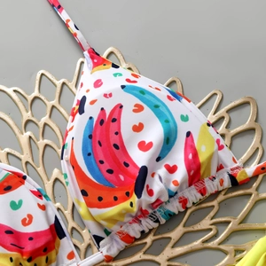 Detail of triangle bikini top with colorful banana and heart print on a textured background