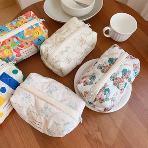 Set of five cute floral and bear pattern quilted cotton makeup bags on a wooden desk