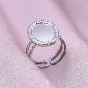 Detailed close-up of a silver stainless steel oval signet ring on pink satin fabric