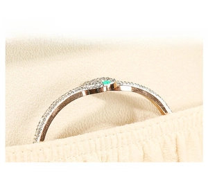 Detailed macro view of gold snake ring with green emerald stone and pavé zircon stones